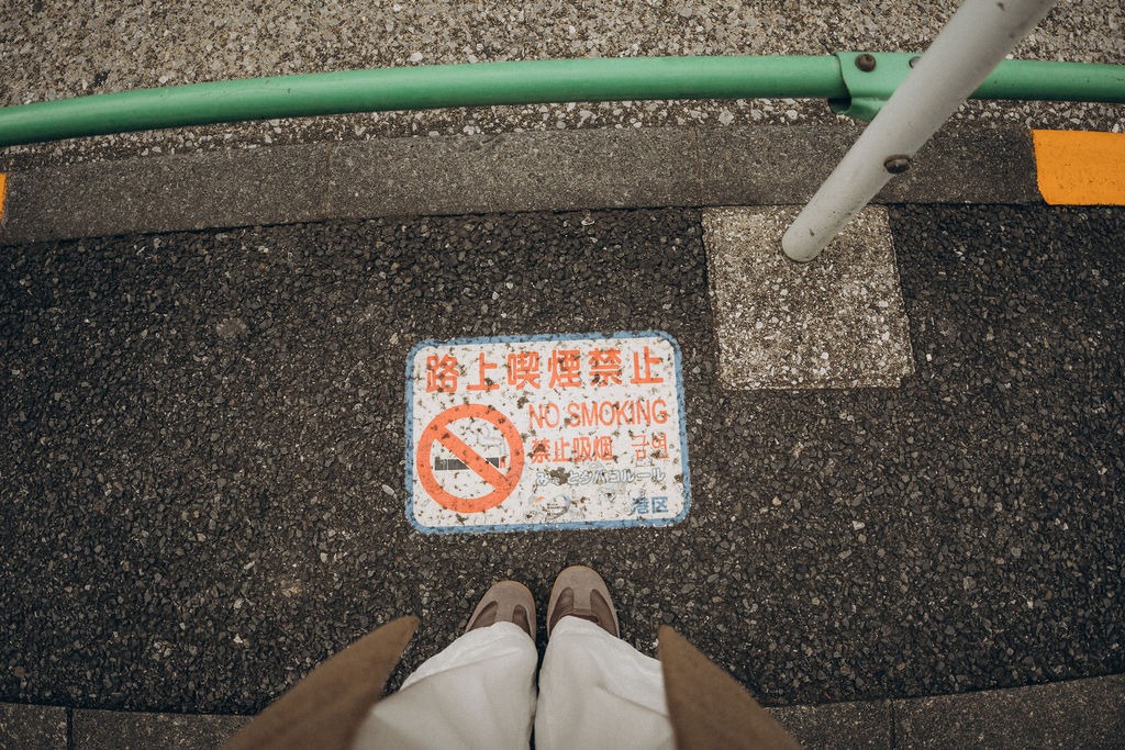 Füße und ein Hinweisschild auf dem Gehweg in Tokio
