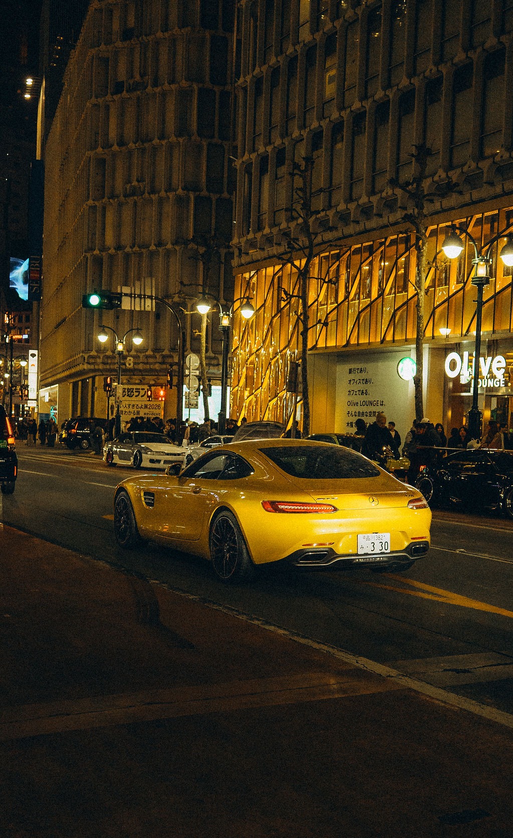 Gelber Sportwagen vor beleuchteten Gebäuden in Tokio bei Nacht