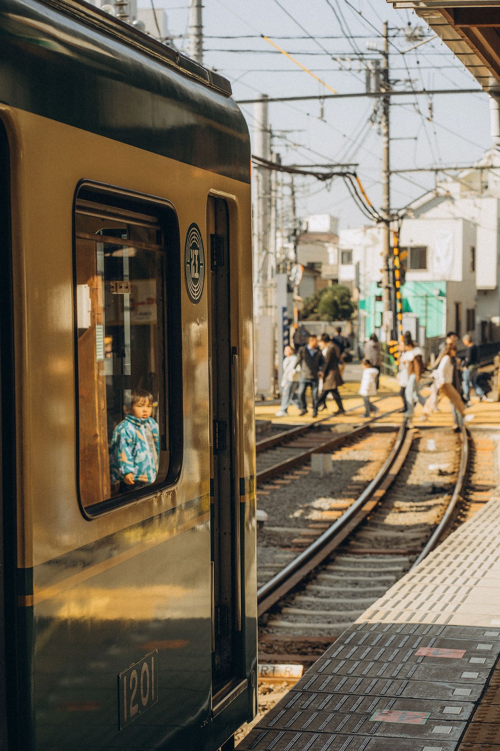 Bahn fährt durch eine schmale Straße zwischen Häusern in Japan