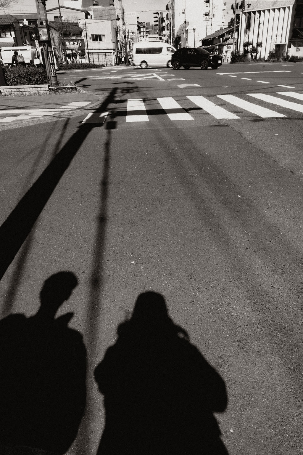 Schwarz-Weiß-Aufnahme mit zwei Schatten auf einer Straße in Tokio