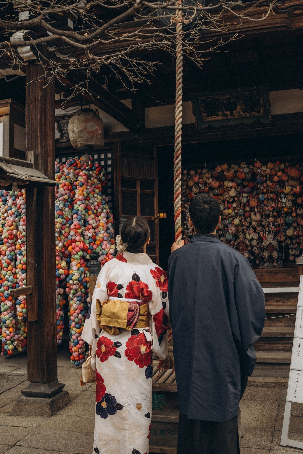 Paar im Kimono vor bunten Stoffbällen am Yasaka Koshindo in Kyoto