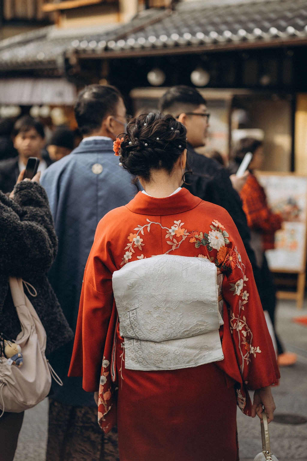 Frau im roten Kimono von hinten in einer Gasse in Kyoto