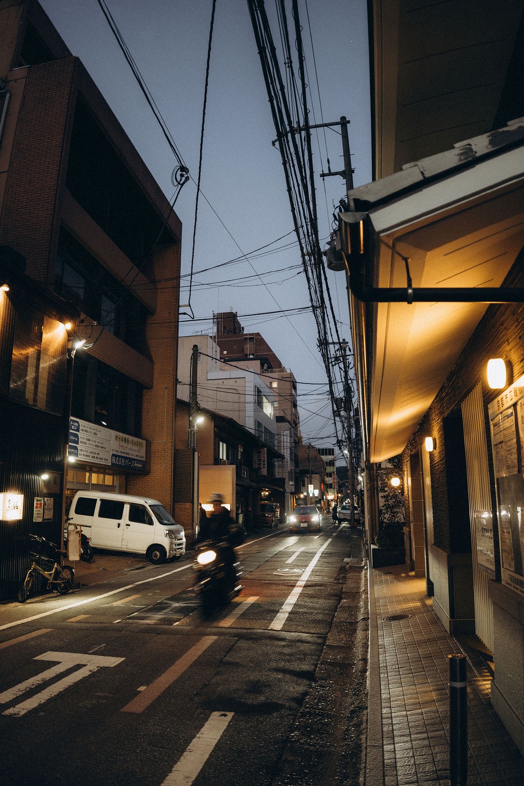 Nächtliche Seitenstraße mit Laternen und Motorroller in Tokio