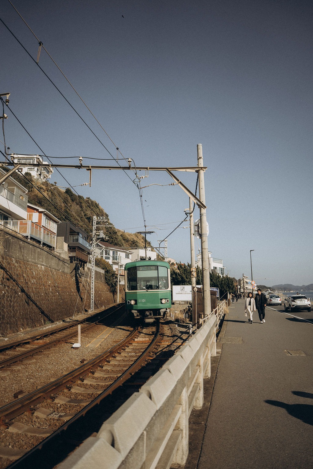 Grün-weiße Bahn fährt an der Küste bei Kamakura entlang