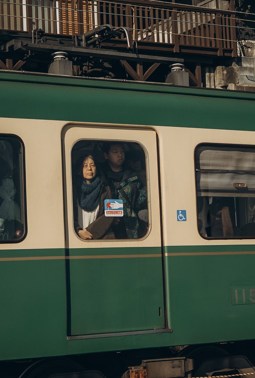 Grün-weiße Bahn mit Fahrgast am Fenster bei Kamakura