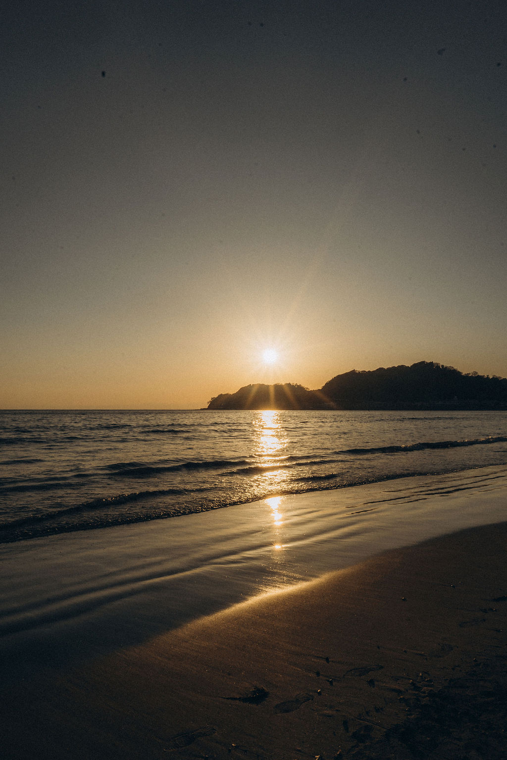 Sonnenuntergang am Strand mit Insel im Hintergrund, Japan